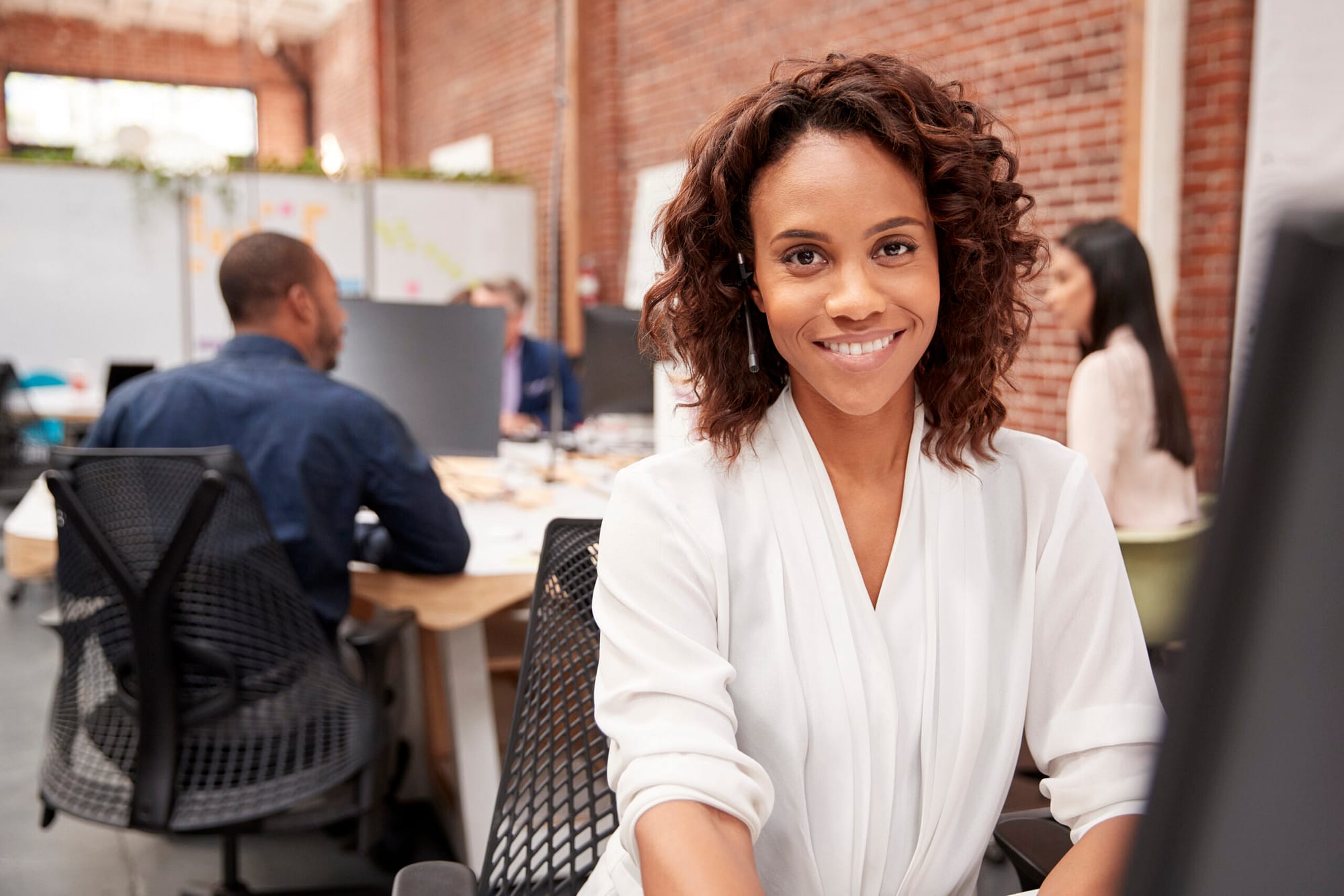 Portrait Of Female Customer Services Agent Working At Desk In Call Center